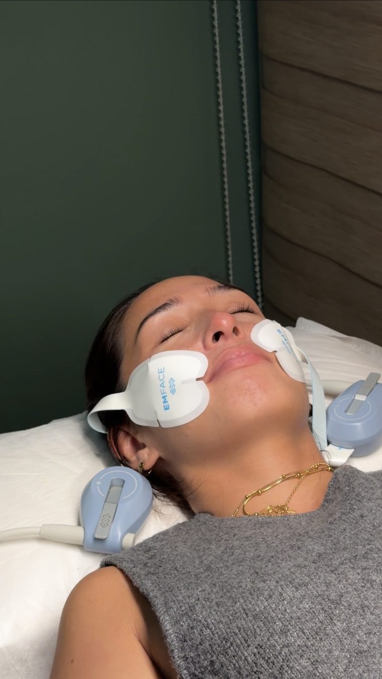 Patient receiving EmFace treatment with applicators on the cheeks at Skinstitute.
